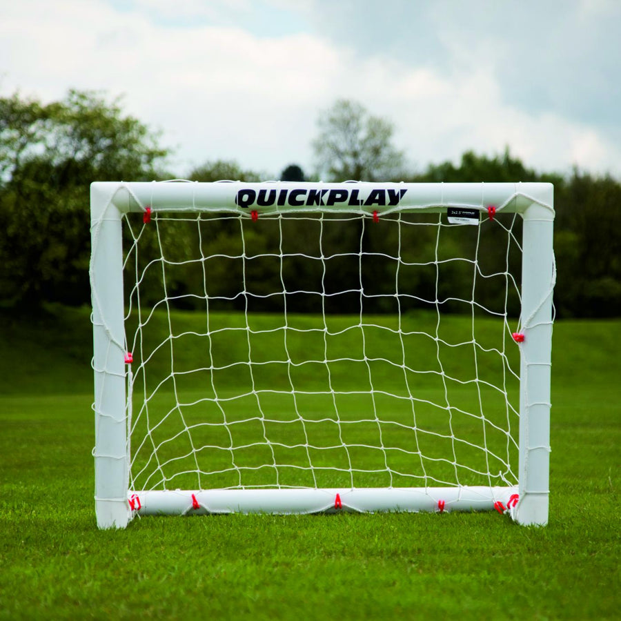 Miniportería de fútbol Q-FOLD 90 x 75 cm vista de frente sobre hierba, con QUICKPLAY en el larguero blanco.