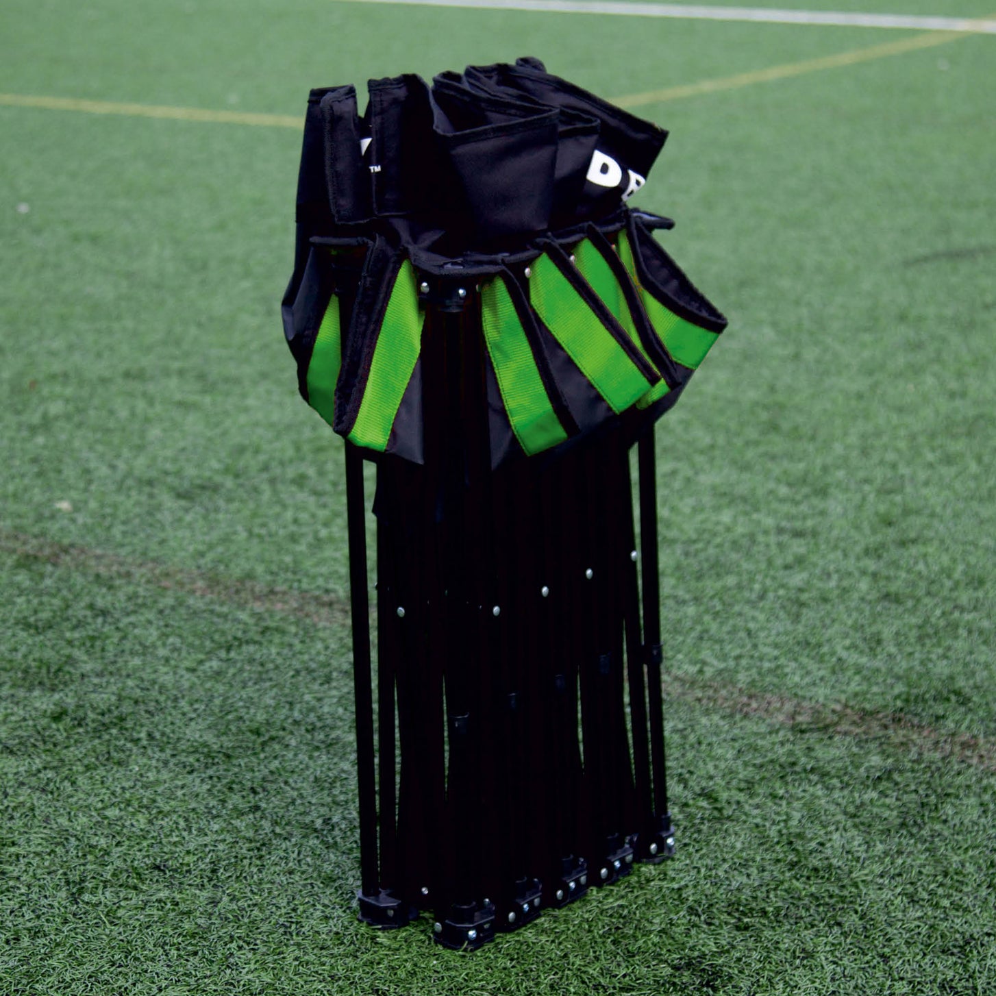 Banquillo de suplentes PRO Bench de 9 plazas plegado en vertical sobre césped artificial, con los asientos agrupados arriba y detalles verdes.