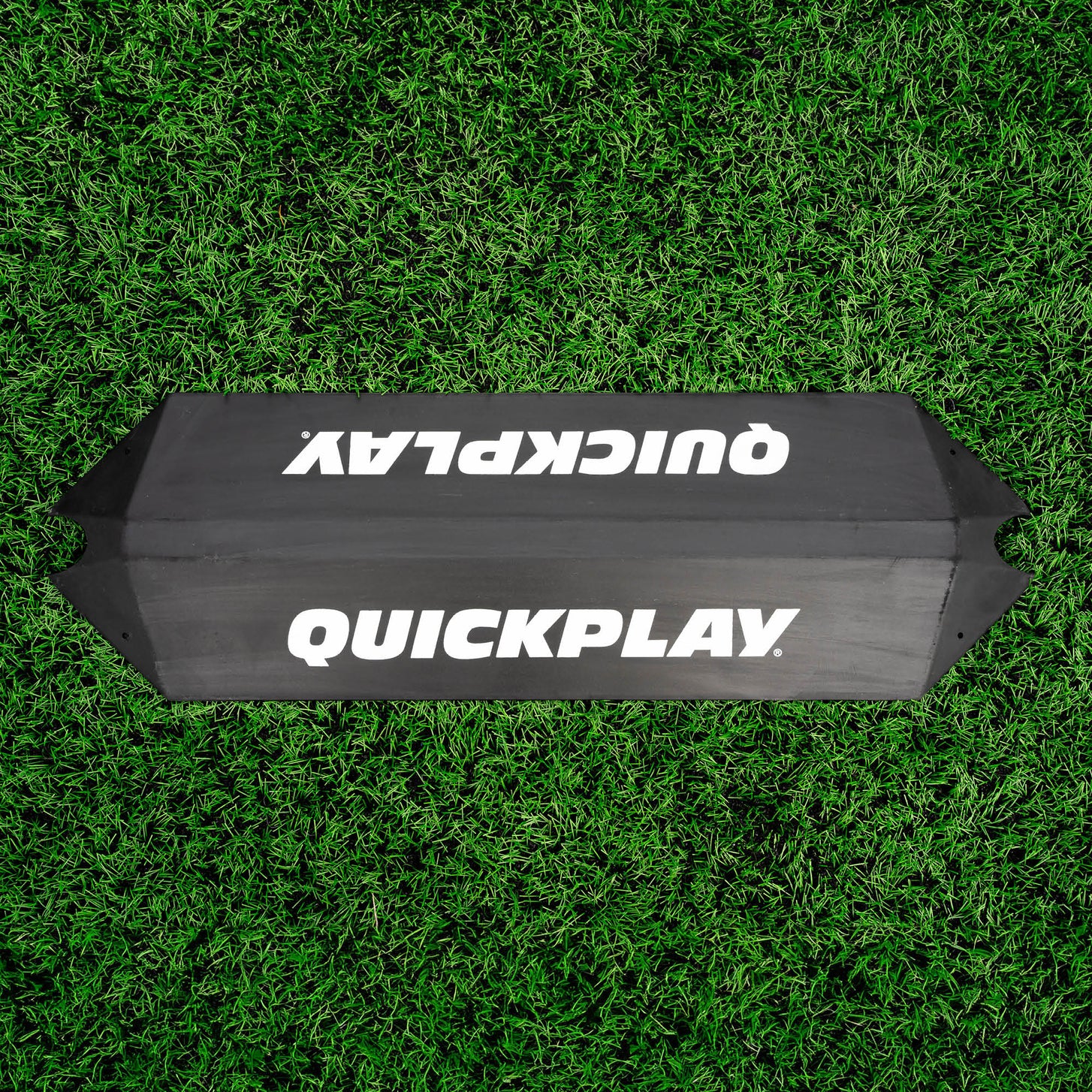 Rampa de rebote para entrenamiento de porteros vista desde arriba sobre césped artificial, con un logotipo QUICKPLAY en cada cara inclinada.