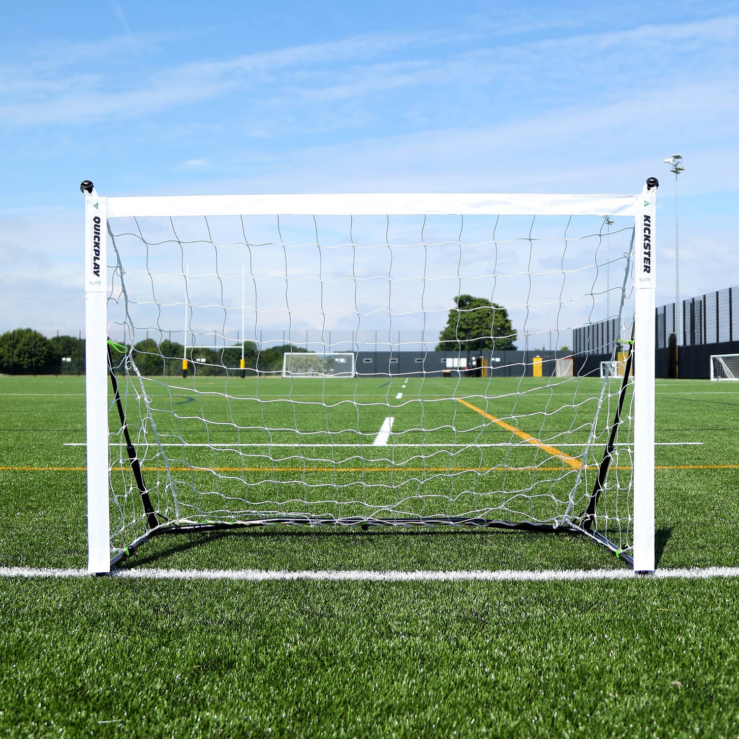 Portería KICKSTER Elite 150 x 100 cm vista de frente, con red blanca, sobre la línea de un campo de césped artificial.