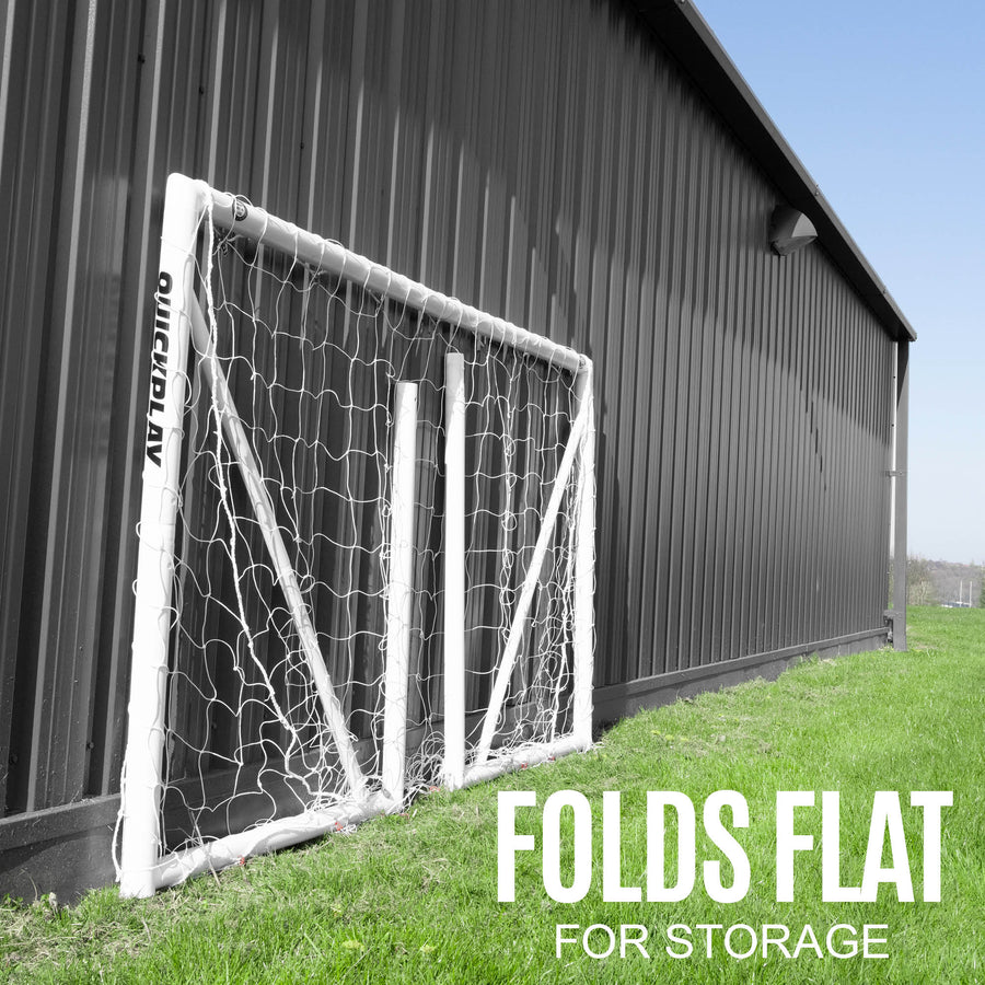 Portería de fútbol Q-FOLD 240 x 150 cm plegada y apoyada contra un edificio metálico oscuro, con el texto "folds flat for storage".