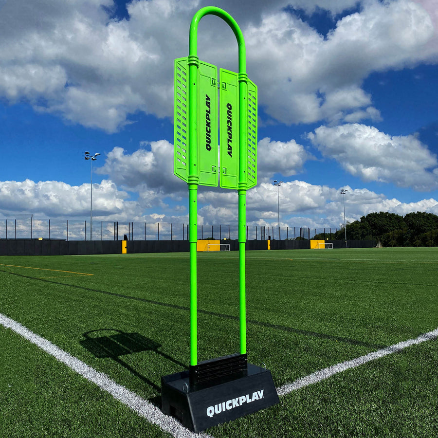 Maniquí de defensa REPLAY con base de rebote Block: maniquí verde con paneles QUICKPLAY de pie en una base negra QUICKPLAY en un campo de césped artificial.